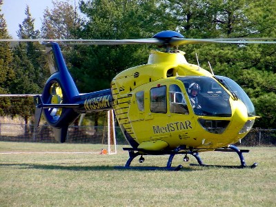 A blue and yellow helicopter with 'MedSTAR' on the side sits on a grass field.