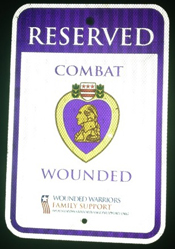A purple heart reserved parking sign. It reads 'RESERVED - COMBAT - WOUNDED' and displays an image of a purple heart medal.